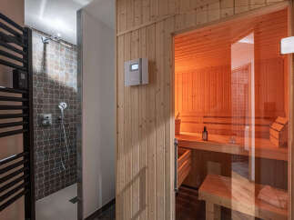 Experience ultimate relaxation in this modern spa area, featuring a sleek shower with geometric tilework and a luxurious, glass-enclosed sauna.