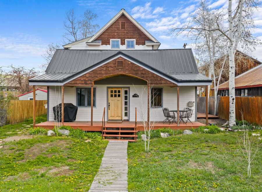 Charming two-story home with a welcoming front porch and a beautifully landscaped yard.