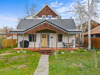 Charming two-story home with a welcoming front porch and a beautifully landscaped yard.