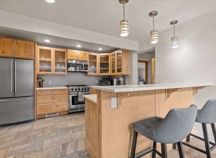 Step into this inviting kitchen, featuring a modern stainless steel refrigerator and a stylish breakfast bar.