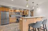 Step into this inviting kitchen, featuring a modern stainless steel refrigerator and a stylish breakfast bar.