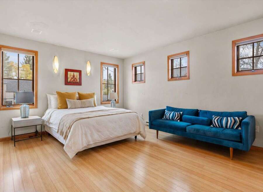 This inviting bedroom boasts a cozy ambiance with its hardwood floors and ample natural light streaming through the windows.