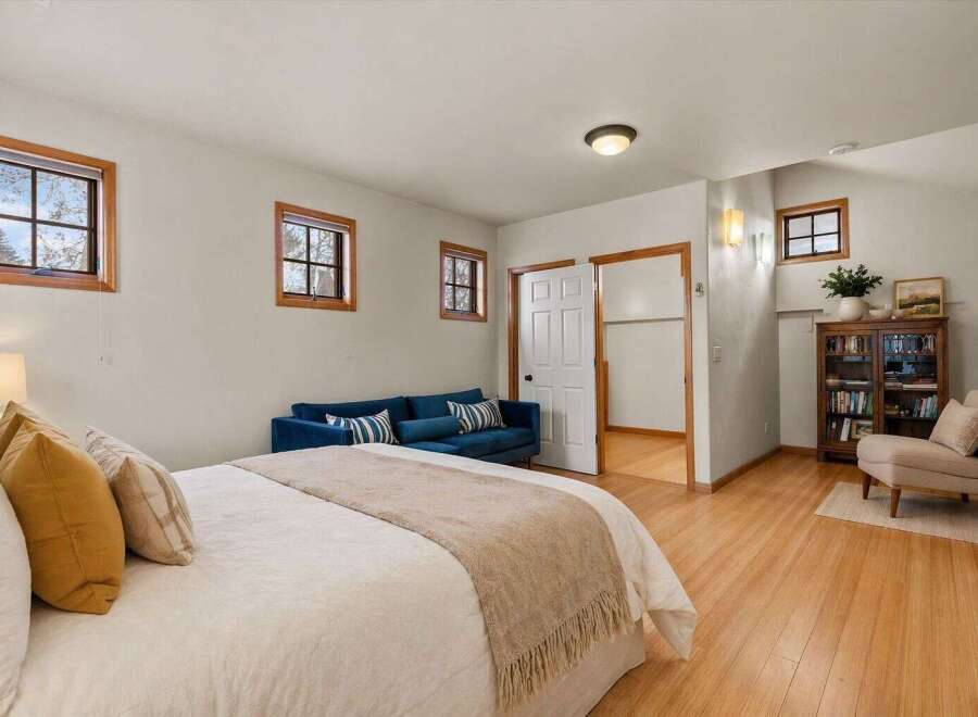 This inviting bedroom boasts a cozy ambiance with its plush bed, complemented by a stylish blue sofa.