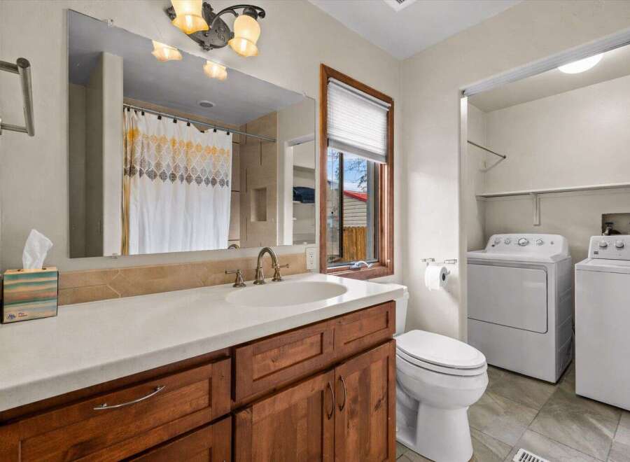 This bathroom features a stylish vanity with a sink and ample storage, complemented by a large mirror and elegant lighting fixtures.