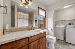 This bathroom features a stylish vanity with a sink and ample storage, complemented by a large mirror and elegant lighting fixtures.