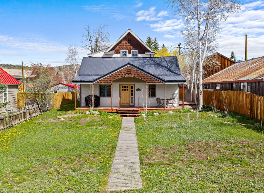 Charming cottage-style home with a welcoming front porch and a beautiful wooden walkway.