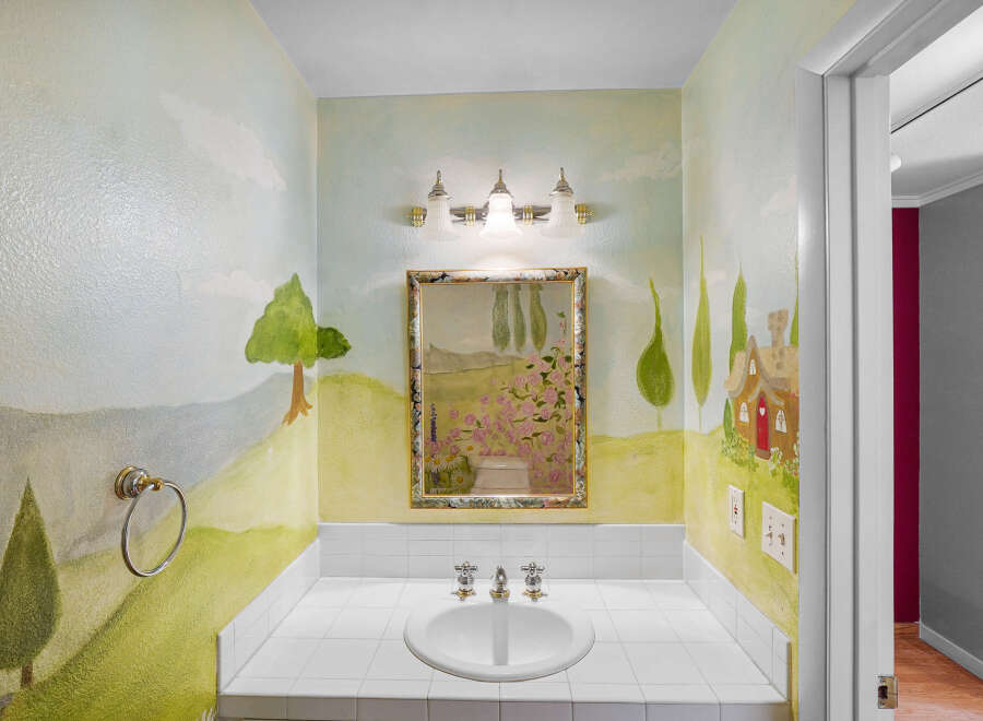Step into a whimsical powder room with enchanting hand-painted murals.