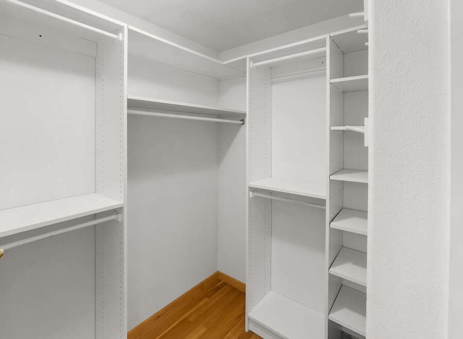 Step into this spacious walk-in closet, offering ample storage with its custom shelving and hanging rods.