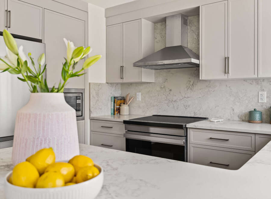 This modern kitchen boasts sleek cabinetry, stainless steel appliances, and a stunning marble backsplash.