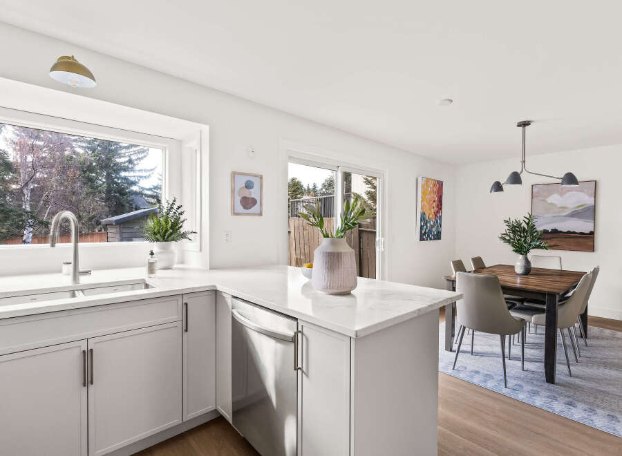 This stunning kitchen boasts a modern design with sleek white cabinetry and a spacious layout.