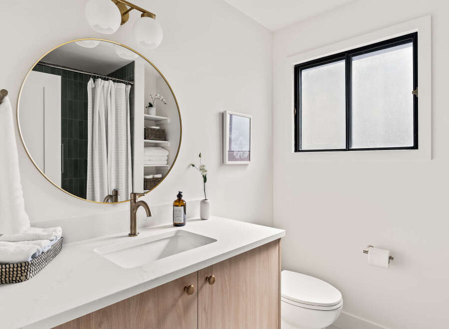 This modern bathroom features a sleek design with a round mirror, a stylish faucet, and a clean white countertop.