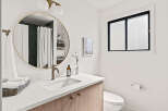 This modern bathroom features a sleek design with a round mirror, a stylish faucet, and a clean white countertop.
