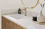 This stunning bathroom features a modern design with a sleek white countertop and a stylish gold faucet.