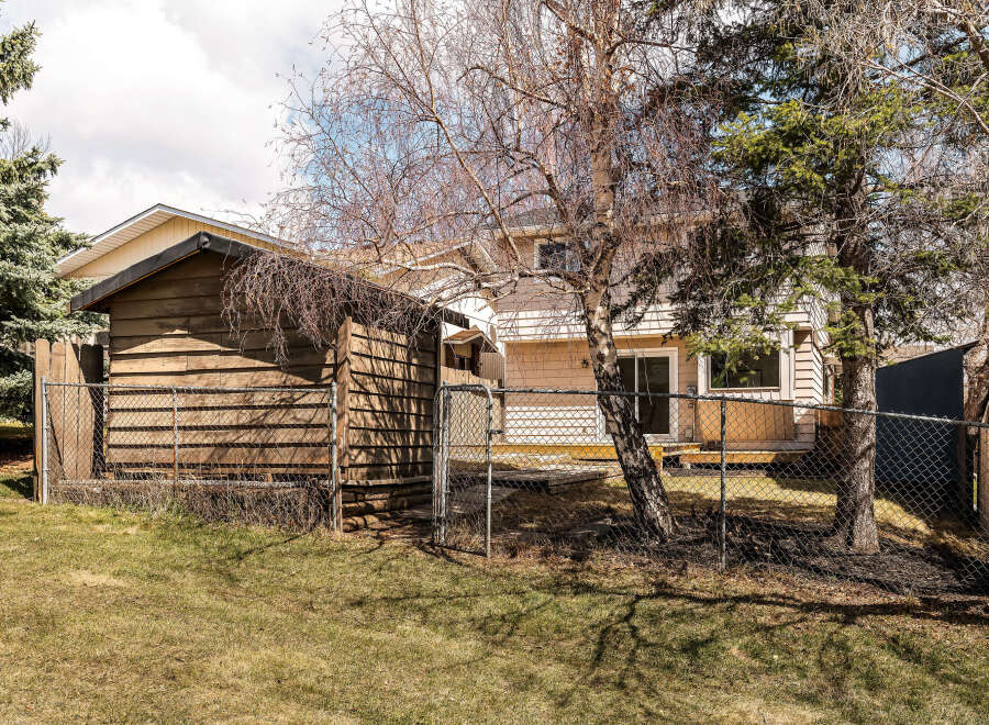 Discover the charm of this property, featuring a well-maintained wooden shed and a secure chain-link fence.