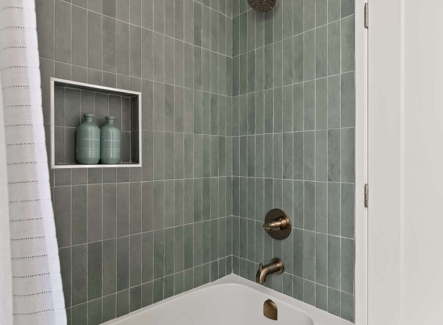 This modern bathroom features a sleek, white bathtub and stylish gray tile walls.