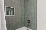 This modern bathroom features a sleek, white bathtub and stylish gray tile walls.