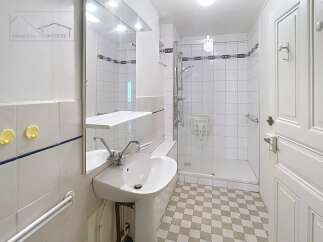 Discover this charming bathroom featuring a modern pedestal sink and a convenient shower area.