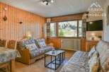 Discover the charm of this cozy property, featuring a warm wooden interior and comfortable seating arrangements.