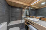 This modern bathroom features a sleek design with gray tiled walls and a wooden ceiling, creating a warm and inviting atmosphere.