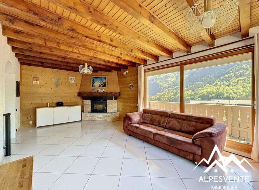 Discover the charm of this stunning property, featuring a cozy living room with a fireplace and a beautiful wooden ceiling.