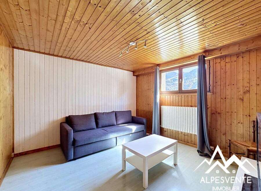 Discover this charming property featuring a cozy living space with wooden paneling and a comfortable sofa.