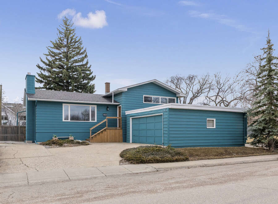 This charming home boasts a striking teal exterior, offering curb appeal.