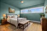 This charming bedroom boasts a serene ambiance with its calming teal walls and natural wood flooring.