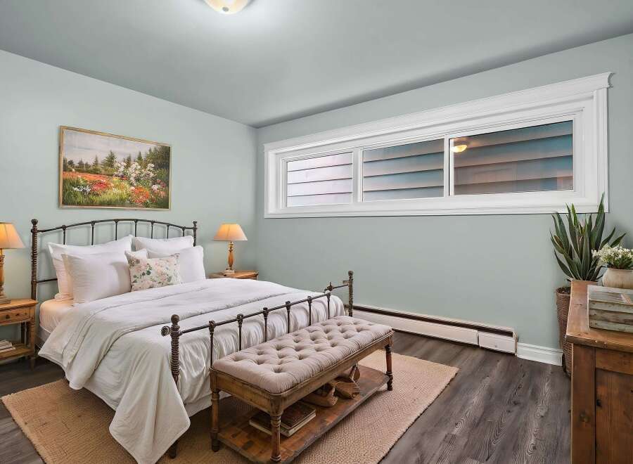 This inviting bedroom showcases a blend of comfort and style, featuring a cozy bed, a charming bench, and a touch of nature with a potted plant.