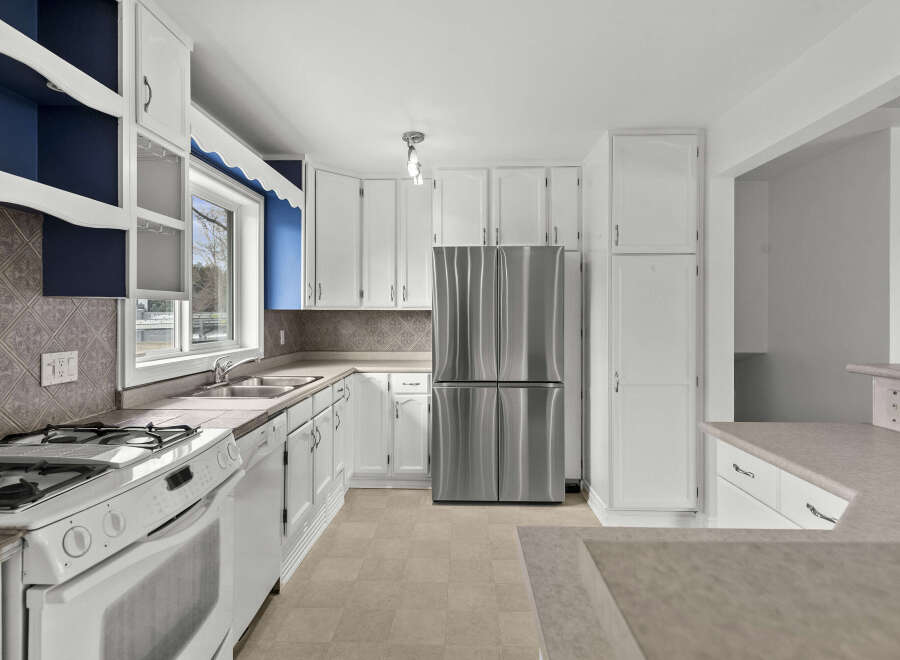 This bright and airy kitchen features white cabinetry, offering ample storage space.