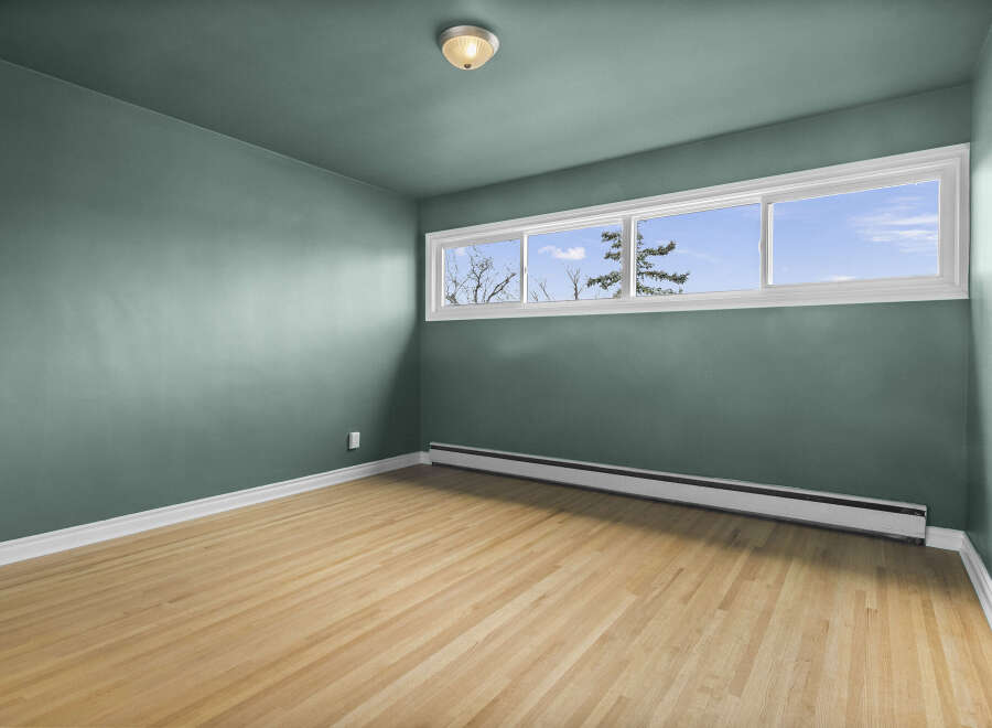 This inviting room features a fresh, modern aesthetic with its light-toned hardwood floors and calming teal walls.