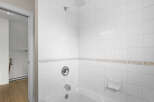 This pristine bathroom features a clean, modern design with white tile walls and a matching bathtub.
