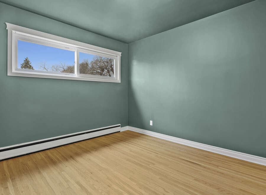 This inviting room features a fresh, modern aesthetic with its soothing teal walls and natural wood flooring.