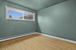 This inviting room features a fresh, modern aesthetic with its soothing teal walls and natural wood flooring.