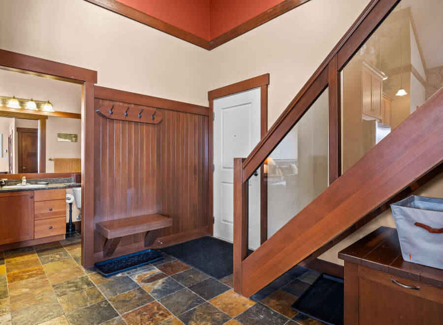 Step into this inviting entryway, showcasing a stunning staircase with glass paneling and rich wood accents.