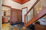 Step into this inviting entryway, showcasing a stunning staircase with glass paneling and rich wood accents.