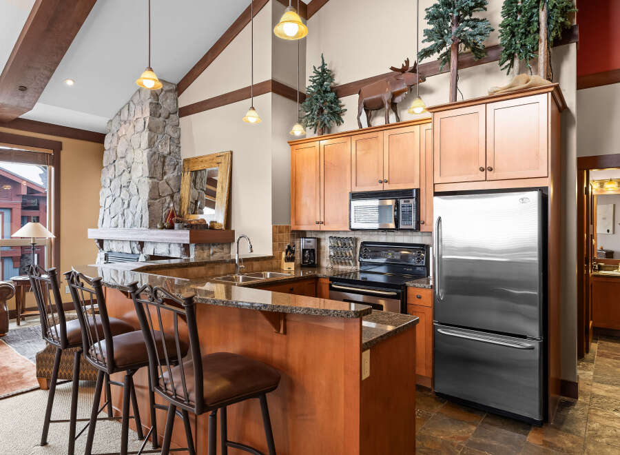 This stunning kitchen boasts a rustic charm with its stone fireplace and wooden cabinetry.