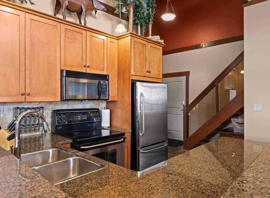 This stunning kitchen boasts beautiful wooden cabinetry, a modern stainless steel refrigerator, and a sleek black stovetop.