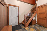 Step into this inviting entryway, showcasing a stunning staircase with glass panels and rich wooden accents.