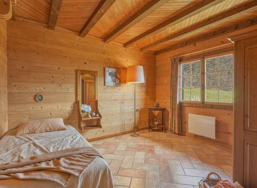 Step into a cozy bedroom retreat with warm wooden walls and a charming ambiance.