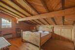 Step into this charming wooden bedroom, a cozy retreat with a unique sloped ceiling design.