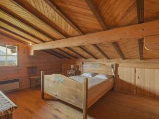 Step into this charming wooden bedroom, a cozy retreat with a unique sloped ceiling design.