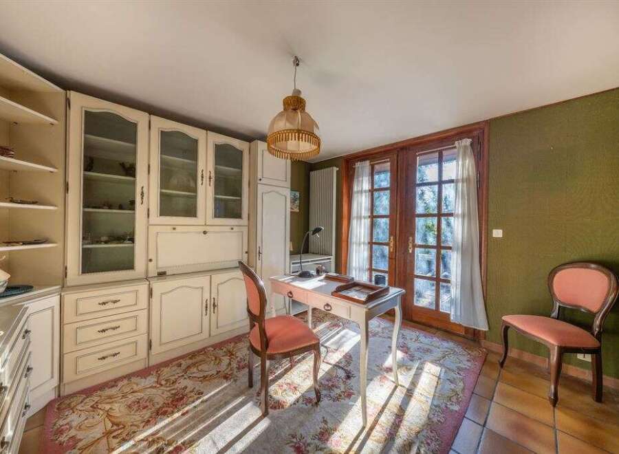 Step into this charming home office, featuring a classic design with built-in cabinetry and a cozy ambiance.