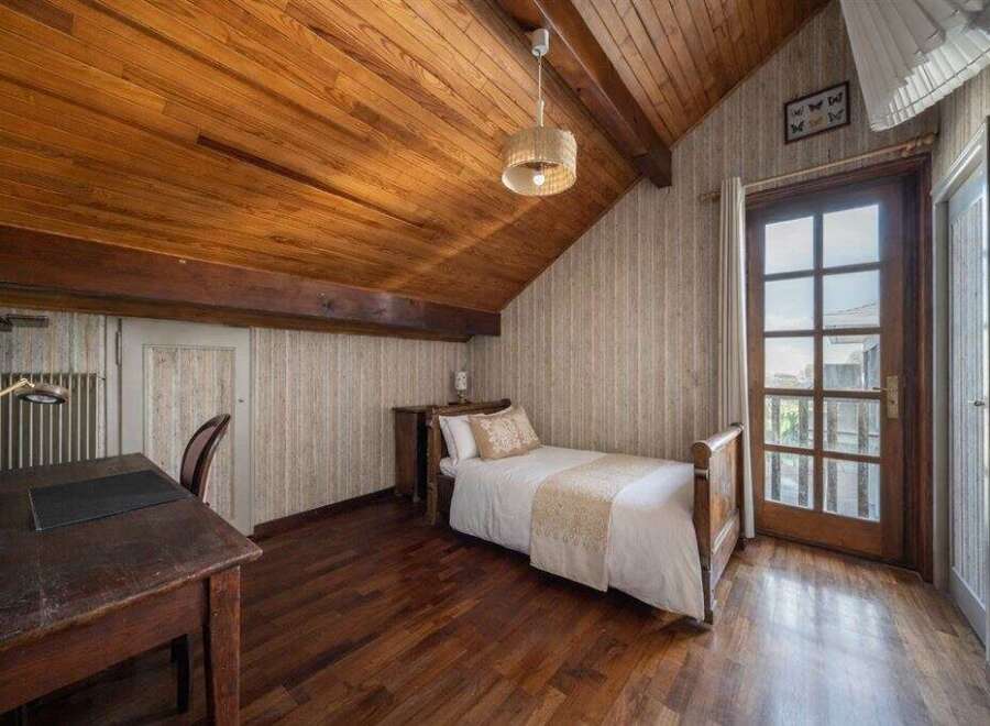 This charming bedroom features a warm wooden ceiling and flooring, creating a cozy and inviting atmosphere.