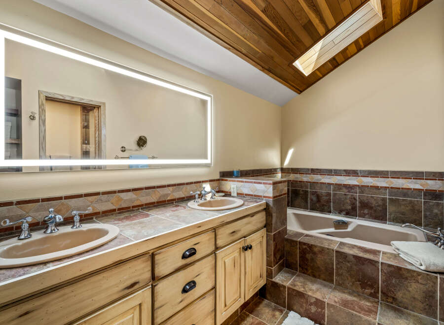 This luxurious bathroom features a stunning wood ceiling with a skylight, creating a bright and airy atmosphere.