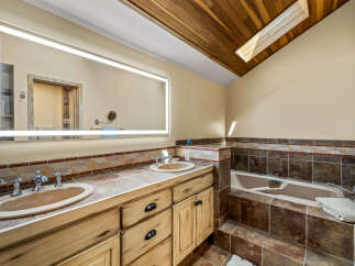 This luxurious bathroom features a stunning wood ceiling with a skylight, creating a bright and airy atmosphere.