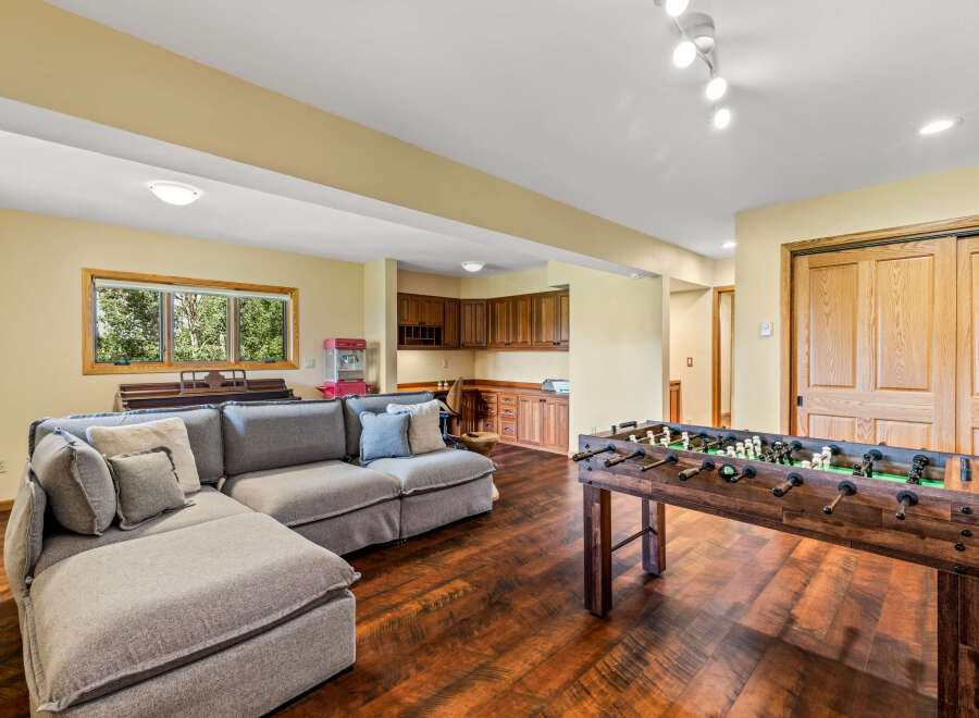 This spacious rec room is perfect for entertaining, featuring a comfortable sectional sofa and a classic foosball table.
