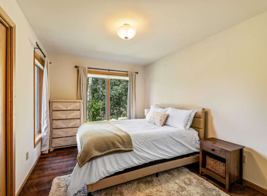 This inviting bedroom offers a serene retreat with its cozy ambiance and natural light.