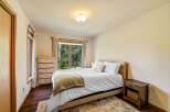 This inviting bedroom offers a serene retreat with its cozy ambiance and natural light.