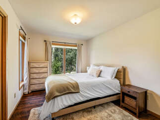 This inviting bedroom offers a serene retreat with its cozy ambiance and natural light.