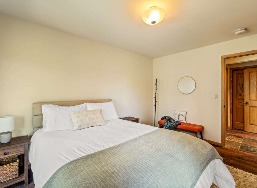 This cozy bedroom features a comfortable bed with soft linens and a stylish throw blanket, perfect for a relaxing retreat.